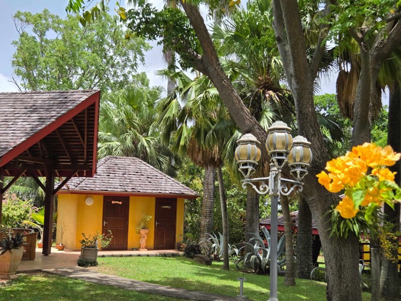 Bungalow jaune, lampadaire ancien et bougainvillier orange dans le Jardin de Beauvallon, Basse-Terre
